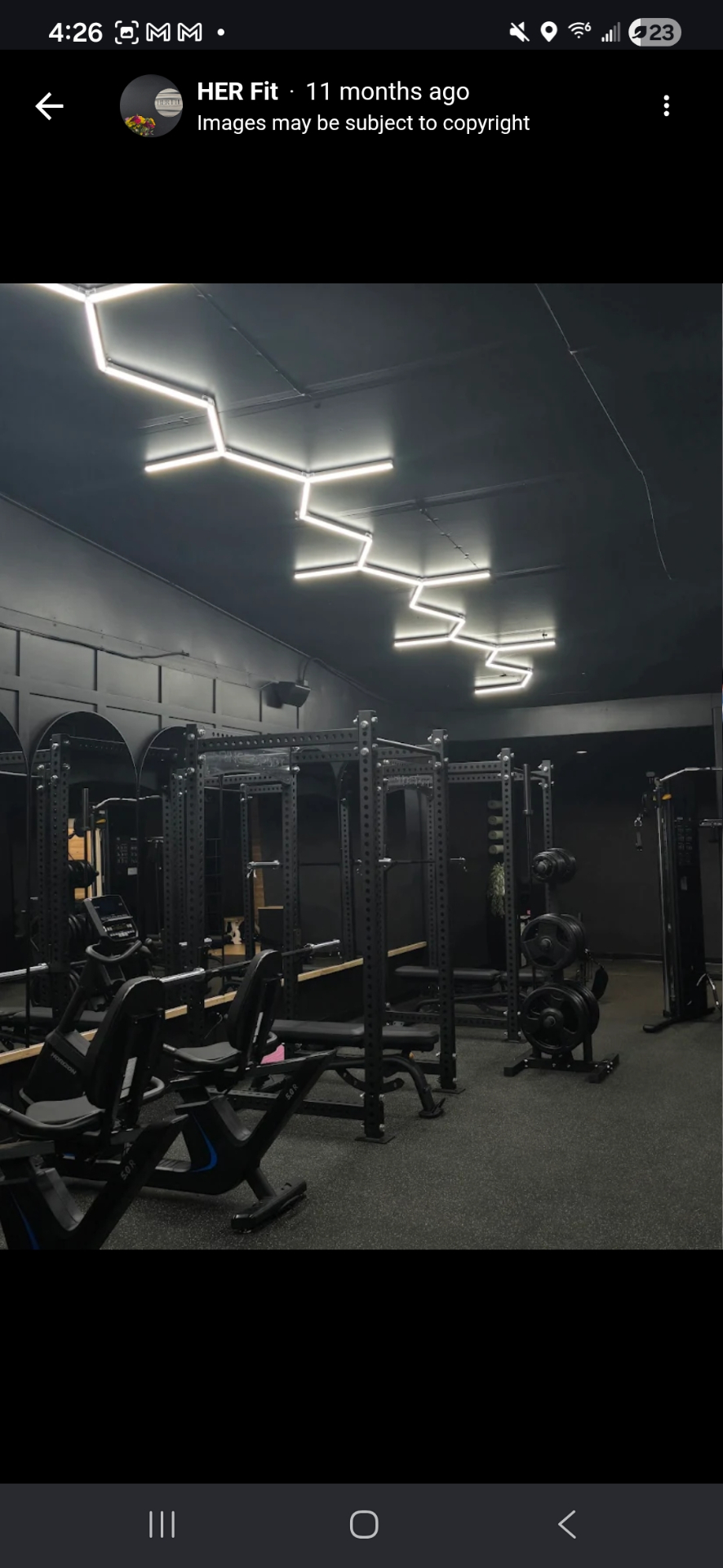 The HER Fit studio interior with squat racks and warm wood floors